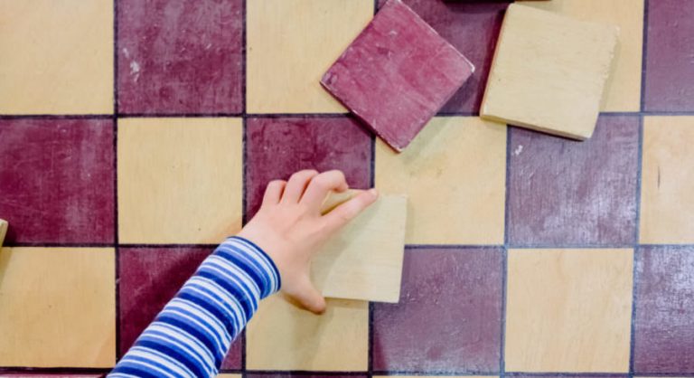 Child's Hand Places The Pieces Of A Checkers Game, Seen From Abo